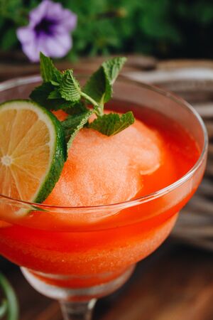 frozen strawberry Margarita cocktail close-up next to flowers on wooden background.の写真素材