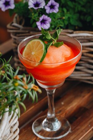 frozen strawberry Margarita cocktail close-up next to flowers on wooden background.の写真素材
