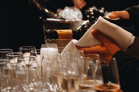 Pouring champagne into wine glasses. Champagne flutes on a wedding or new year eve party.の写真素材