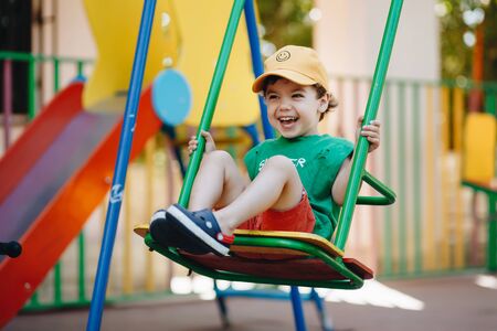 beautiful little boy spinning on a summer swing with space for textの写真素材