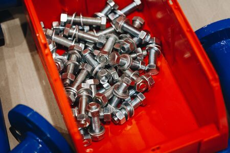 many nuts and bolts of the same size in a red container with space for text.の写真素材