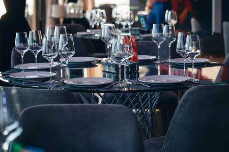 Glasses, flower fork, knife served for dinner in restaurant with cozy interior.の写真素材