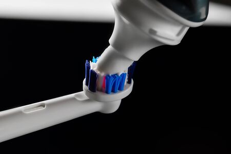 electric toothbrush and white toothpaste on a black dark background with copy space for text.の写真素材