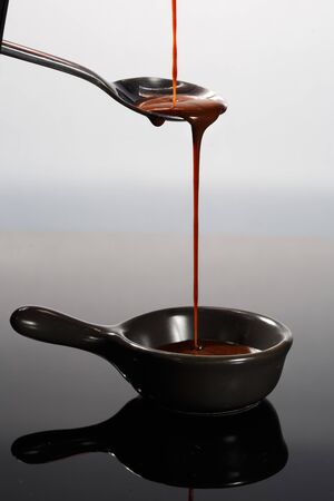 Melted milky brown chocolate pouring from a spoon, isolated on white.の写真素材