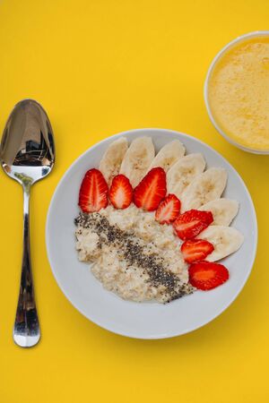 Bowl of breakfast muesli decorated with banana, strawberry slices and chia seed, top view.の写真素材