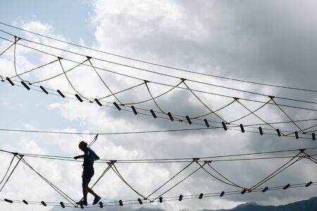 sports male silhouette in a rope Park in a beautiful forest.の写真素材