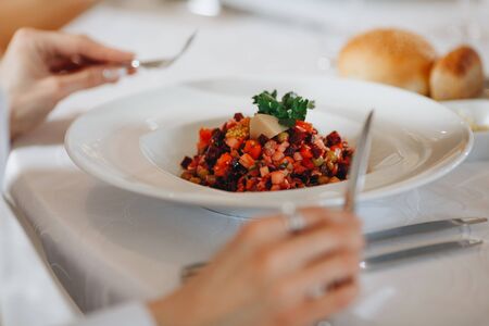Man eats venegret salad in restaurant on white plate close-up.の写真素材