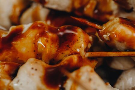 pieces of chicken in a sauce on wooden skewers. close up. の写真素材
