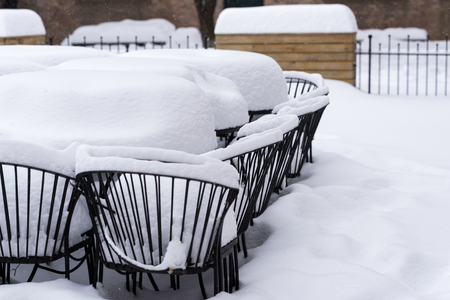 Metal chairs outside under a heavy snowの写真素材