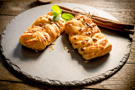 Crusty apple strudel stuffed with apple jam, apple pie sprinkled with walnut and cinnamon stick on...