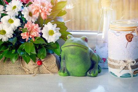 Frog and flowers on the windowsill in vintage style with sunlight.の写真素材