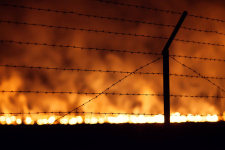 Night fire in a field view through Barbed wireの写真素材