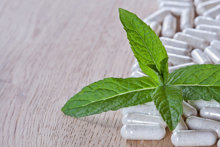 Capsules and a sprig of mint on a wooden surfaceの写真素材