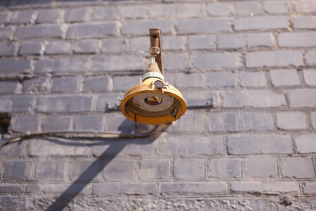 Broken yellow lamp on brick wall backgroundの写真素材