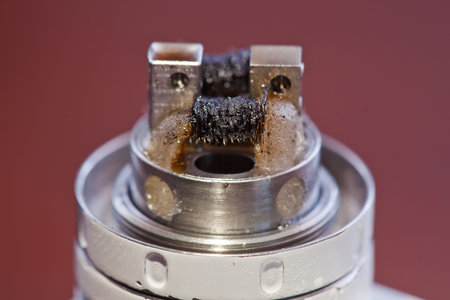 Macro photo of dirty twisted coil mounted in the electronic cigarette.