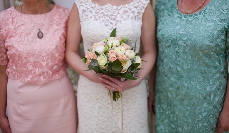 Hands of bride holding a bouquet of roses. Photo with parents.の写真素材