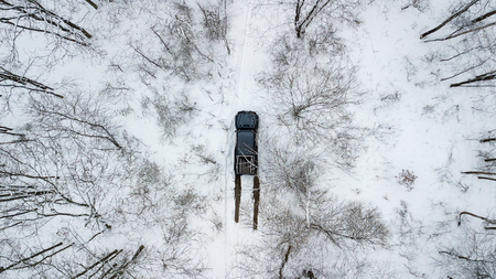 Aerial view on SUV 6x6 that rides by winter road in snow-covered forest.の写真素材