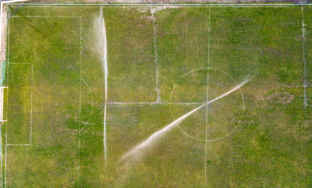 Aerial view of watering the lawn of a football field, top view.の写真素材