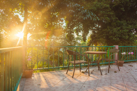 Table and chair on wood deck in the garden with sunset horizontalの写真素材