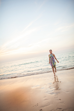 Smiling lady running at the paradise beach on sunset time verticalの写真素材