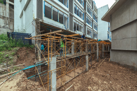 Construction workers working building at construction site. Scaffolding used as temporary staging to work at heightの写真素材