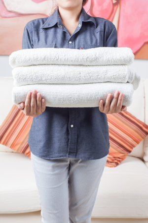 Woman holding stack of fresh towels indoors, closeupの写真素材