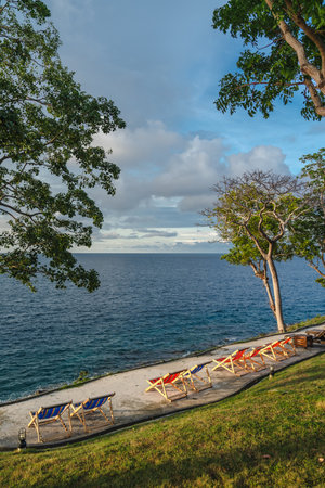 Stunning landscape, sunrise blue sky view with clouds. Tropical resort hotel. Fantastic relax and peaceful vibes, chairs, loungers under umbrella and palm leaves.の写真素材