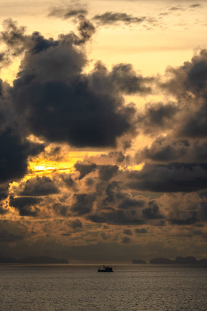 fishing boat sailing across the sea at a golden sunrise with cloudy sky in the morning. Harmony and beauty in nature. Scenic peaceful sea viewの写真素材
