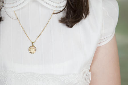detail of a chain and medal of a first communion girl dressed in whiteの写真素材