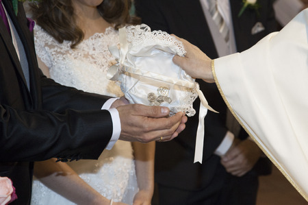 detail of te hands of a priest when he hands the groom the gift to the bride on her wedding dayの写真素材