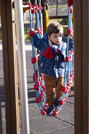two year old boy playing in an outdoor park on a sunny winter day,dressed in a blue coat and brown trousersの写真素材