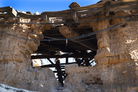 ruins of an old village house made of adobe bricks (mixture of straw and stone mud),where you can see the old wooden beams, the old light cables hanging next to the new cables.の写真素材