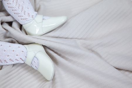 close up of a babyâs feet with white shoes and holes leotards on a light brown backgroundの写真素材