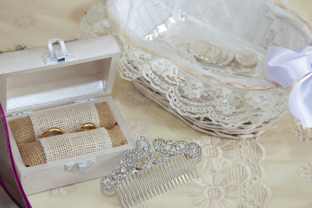 still life on the double bed of the accessories of a bride with arras, a wooden box with the wedding rings and a hair ornamentの写真素材