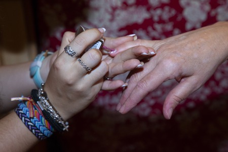 close up of the hands of a teenage girl who is painting her nails to a womanの写真素材