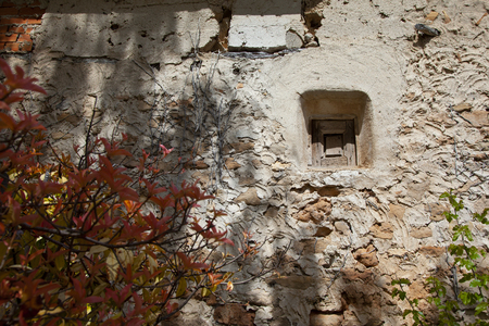 wall of an old town house made of stones, brick, cement, plaster. With areas better preserved than others. The window is very small and wooden os they were before.の写真素材