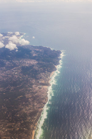 View from the porthole of an airplane. Clouds over Portugal and Atlantic Ocean.