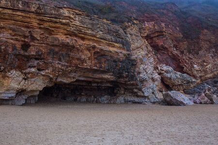 Beach of Nazare, Portugal. Cliff and sand. Caves in the rockの写真素材