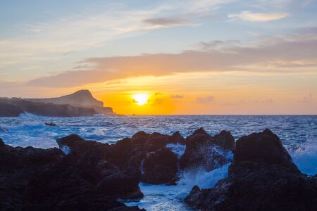 Lava stones on the beach of Piscinas Naturais Biscoitos. Dramatic sunset. Atlantic Ocean. Terceira island Azores, Portugal.の写真素材