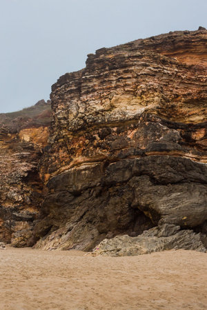 Beach of Nazare, Portugal. Cliff and sand. Caves in the rock