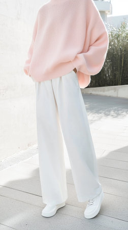 Fashion model showcasing a trendy pastel pink oversized sweater paired with elegant white wide leg trousers, creating a chic and modern look for the upcoming seasonの素材