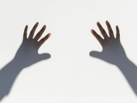 Two hands reaching out create intriguing shadows against a white background, evoking feelings of mystery, longing, and desperation while suggesting themes of connection and hopeの素材
