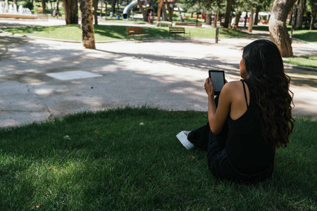 a girl reading an e-book on the lawn