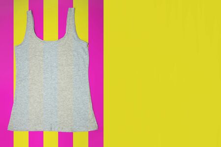 Gray sleeveless female casual tank top on bright striped yellow and pink background. Copyspace. Sport, fitness aparrel. Basic look.の写真素材