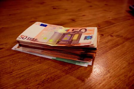 stack of 50 euro bills on a wooden table.の写真素材