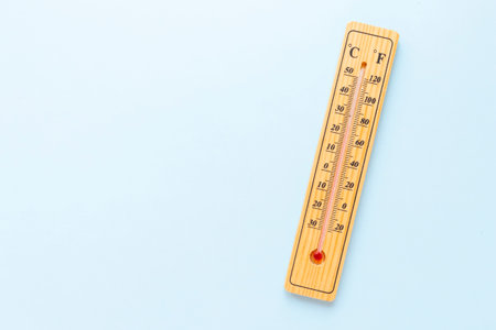 A classic wooden thermometer on blue background doesn't show any temperature