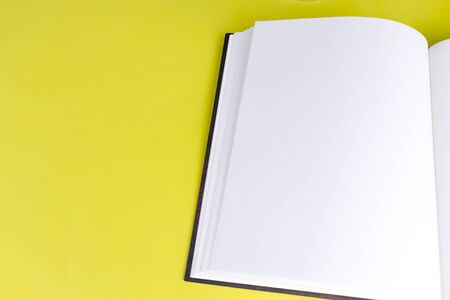 Empty book booklet mockup with blank pages and copy space on yellow background. Top view. Template for magazine, portfolio and catalogueの写真素材