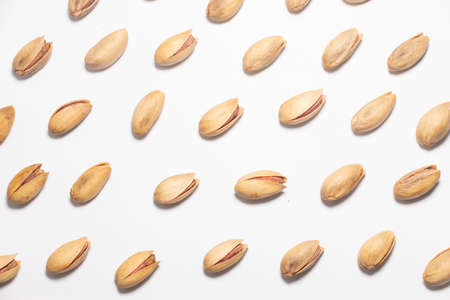 Roasted pistachio nuts pattern on white. Whole fried and dried pistachio nutの写真素材