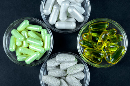 Healthy sport supplements in pills and capsules like vitamins and cod liver oil on dark background