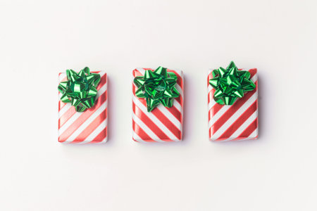 Christmas presents and new year gifts in red striped wrapping paper with green bows on white...